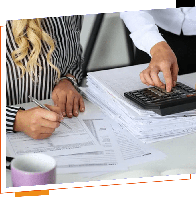 Two people are working on paperwork at a table.